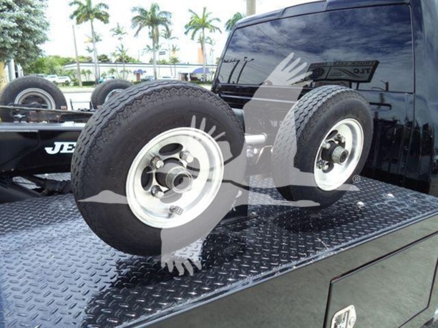 Two spare wheels on a flatbed with diamond plate surface; Ram truck rear window visible; tires mounted on rims; some reflections in the window.