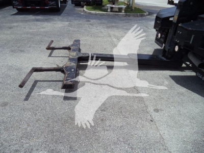 Winch hitch assembly with two long forks and mounting bar, on pavement next to a Ram truck, visible in a used-truck lot.