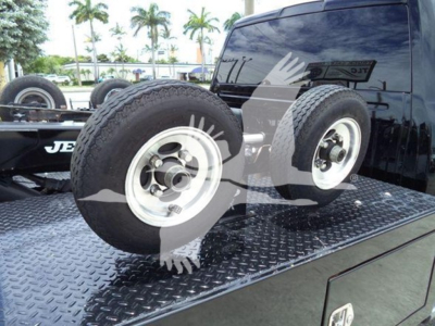 Two spare wheels on a flatbed with diamond plate surface; Ram truck rear window visible; tires mounted on rims; some reflections in the window.