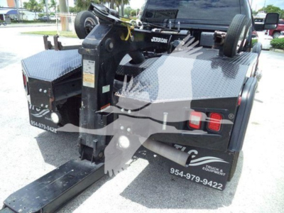 Ram 4500 truck rear with hydraulic tow winch system, aluminum diamond plate bed, mounted hitch, and dual rear lights visible.