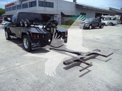 Ram 4500 pickup truck with a front-mounted tow winch and dual metal forks in a dealership lot; black truck, other vehicles in background.