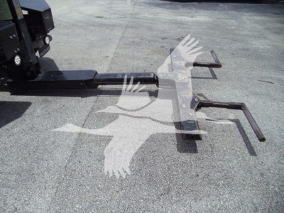 Tow hitch or winch mounting hitch with metal arms and fork-like extensions in a parking lot; no legible labels visible on the component