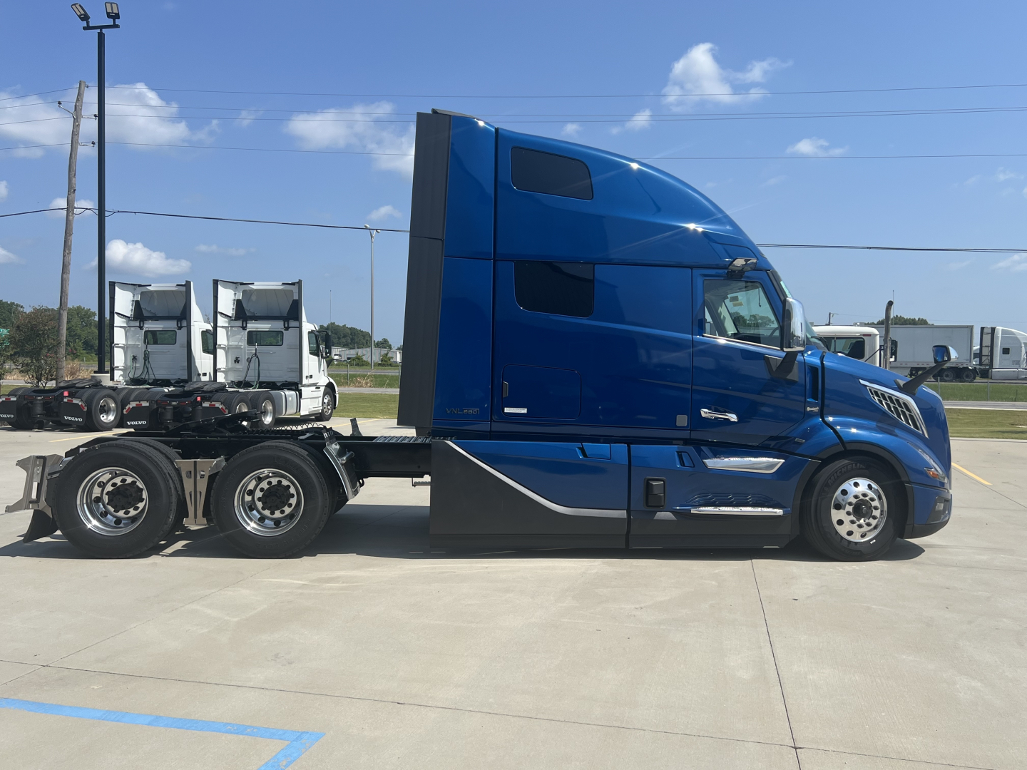 Volvo VNL64T860 semi-truck tractor in blue, side view showing sleeper cab and rear axles.