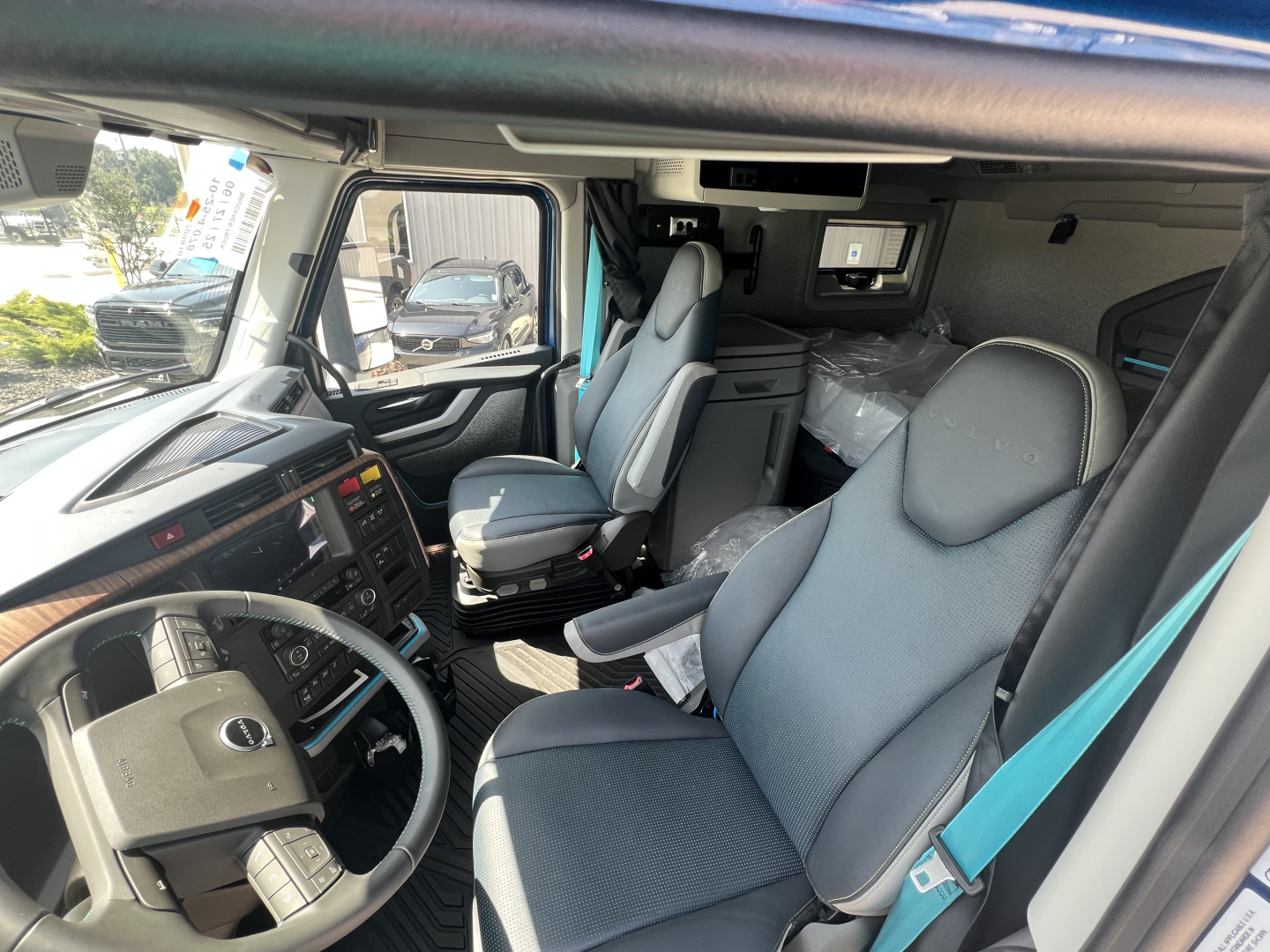 Volvo VNL64T860 interior cab view showing driver and passenger seats, dashboard, steering wheel, and overhead sleeper area.