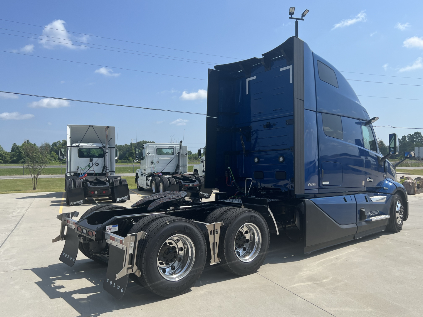 Volvo VNL64T860 truck tractor in blue cab, side view, with sleeper, 6 wheels visible and chrome rims.