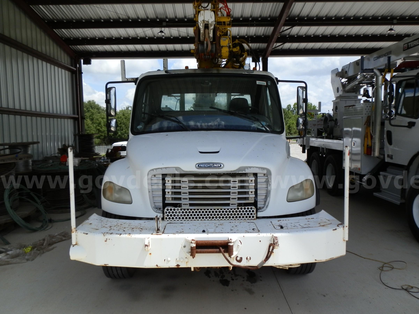 Front view of a Freightliner M2 106 service/utility truck with a heavy-duty bumper and crane equipment overhead.