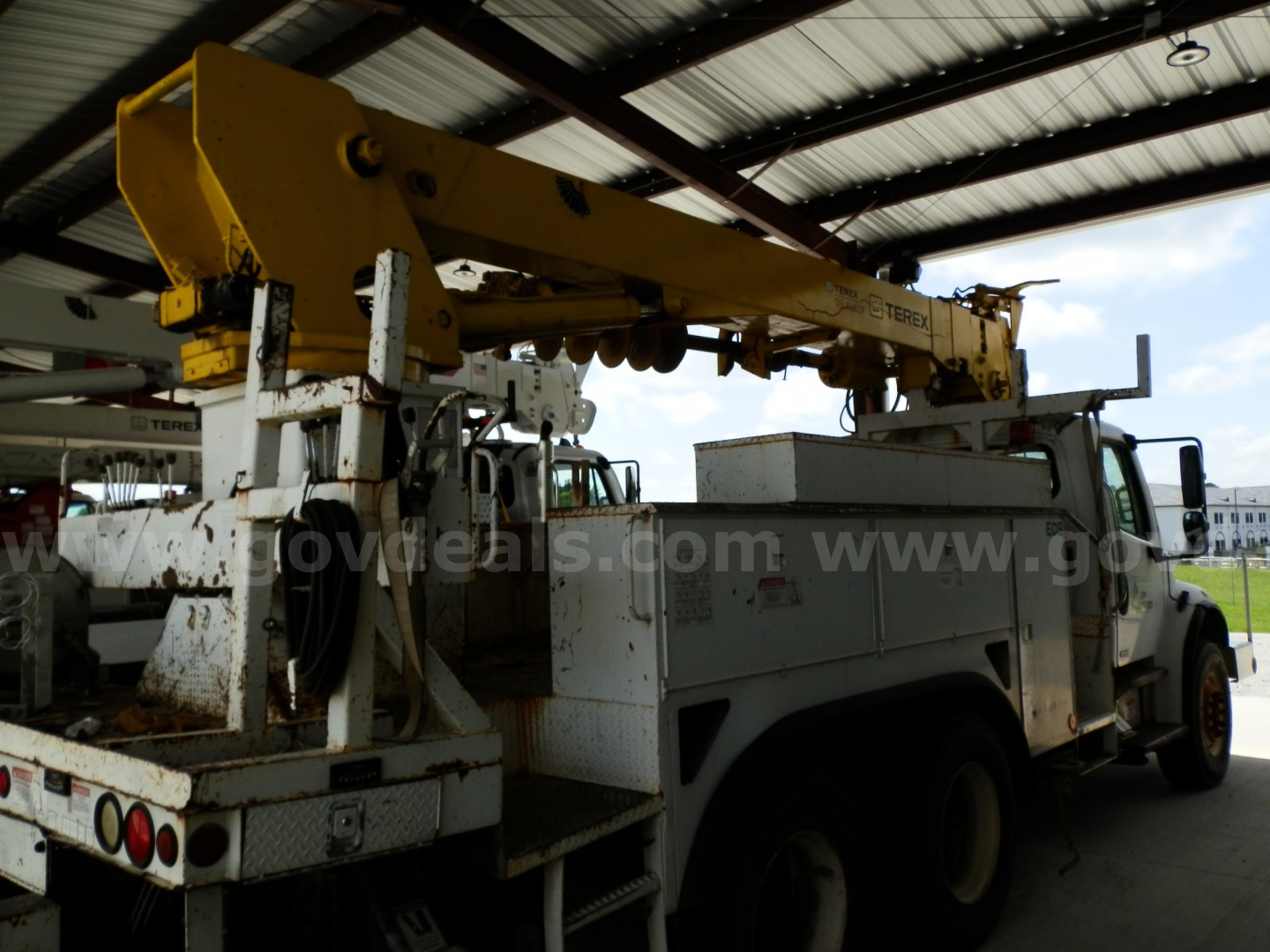 2007 Freightliner M2 106 service truck with boom crane and utility equipment in a covered area.