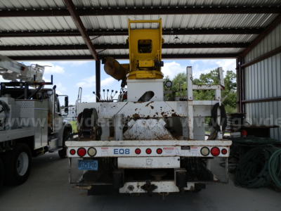 Rear view of a used Freightliner M2 106 service/utility truck with a mounted yellow boom, under a metal canopy.