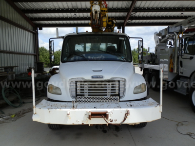 Front view of a Freightliner M2 106 service/utility truck with a heavy-duty bumper and crane equipment overhead.