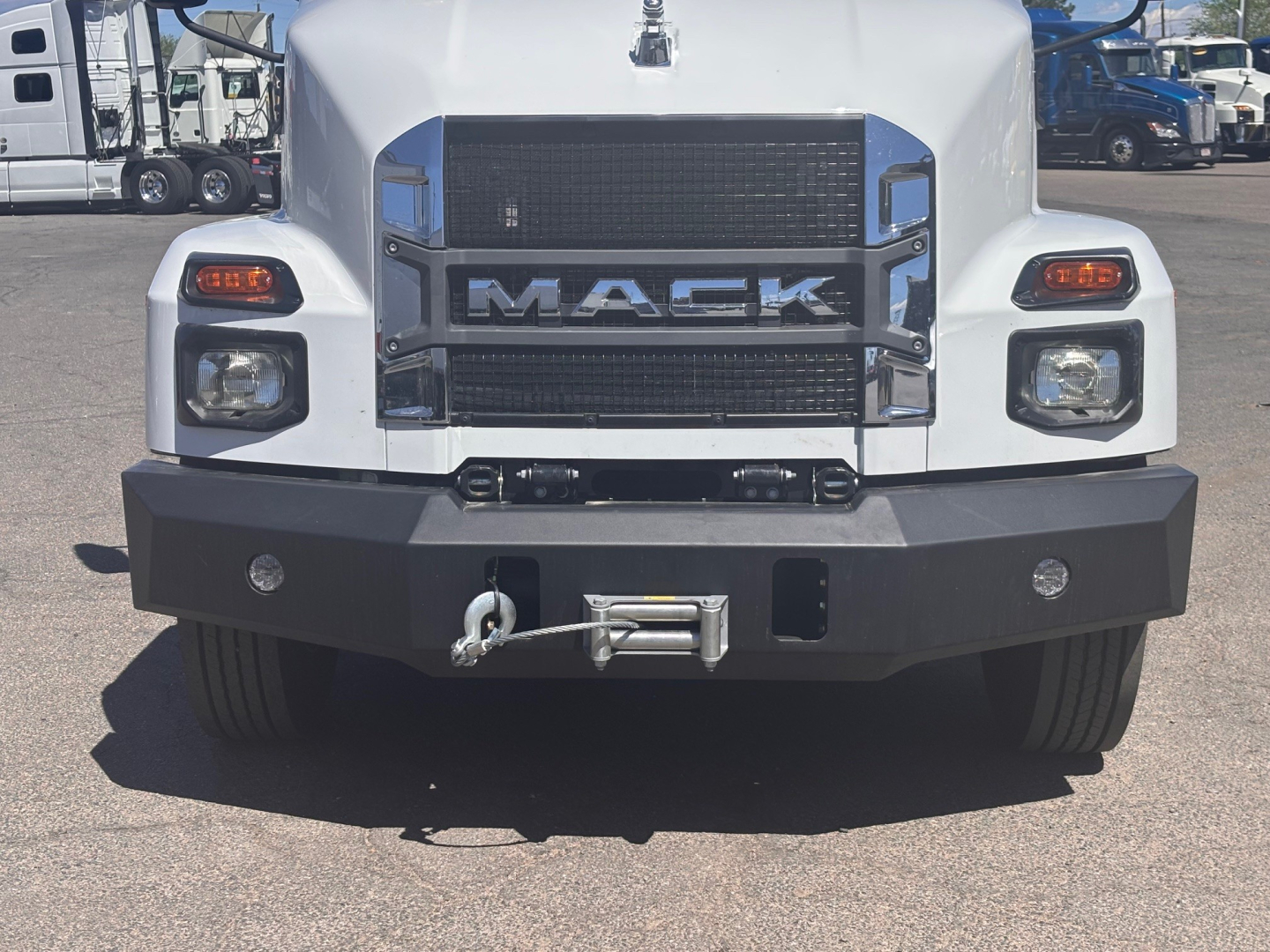 Mack MD7 front view showing grille with MACK letters, bumper with winch, and headlights in a service truck, stock photo style.
