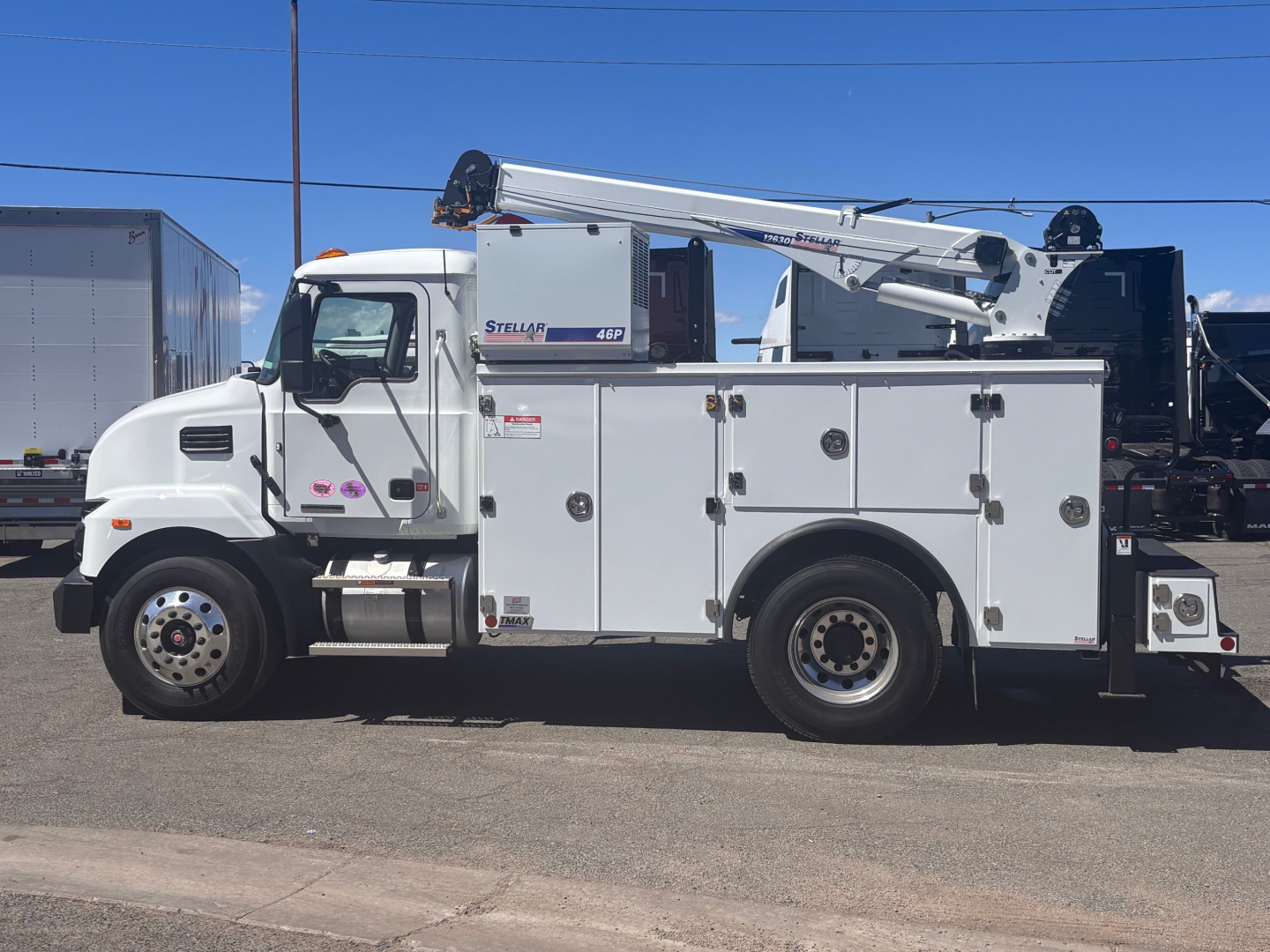 Truck body showing utility service truck with crane mounted on bed, white cab, multiple compartments, and boom crane extended.