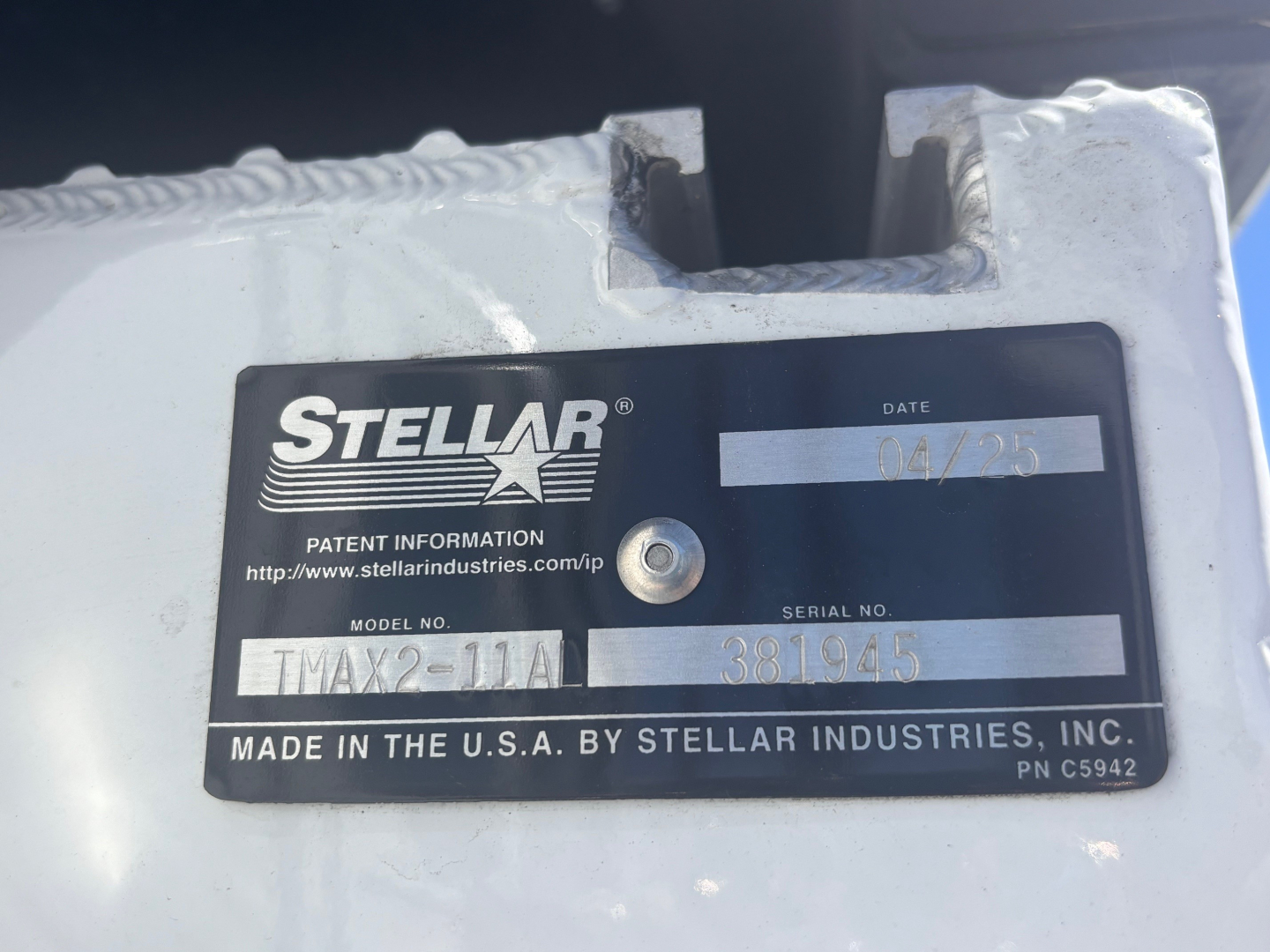 Stellar Industries label plate on a vehicle component showing model TMX??-? and serial number 381945 with date 04/23. The plate reads MADE IN THE U.S.A. BY STELLAR INDUSTRIES, INC. and shows patent info URL www.stellarindustries.com/ip.