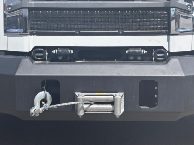 Front bumper of a 2026 Mack MD7 dump truck showing winch and towing hook, heavy grille, and bumper hardware.