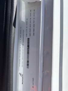 Mack MD7 label/sticker on door jamb showing VIN and stock information.