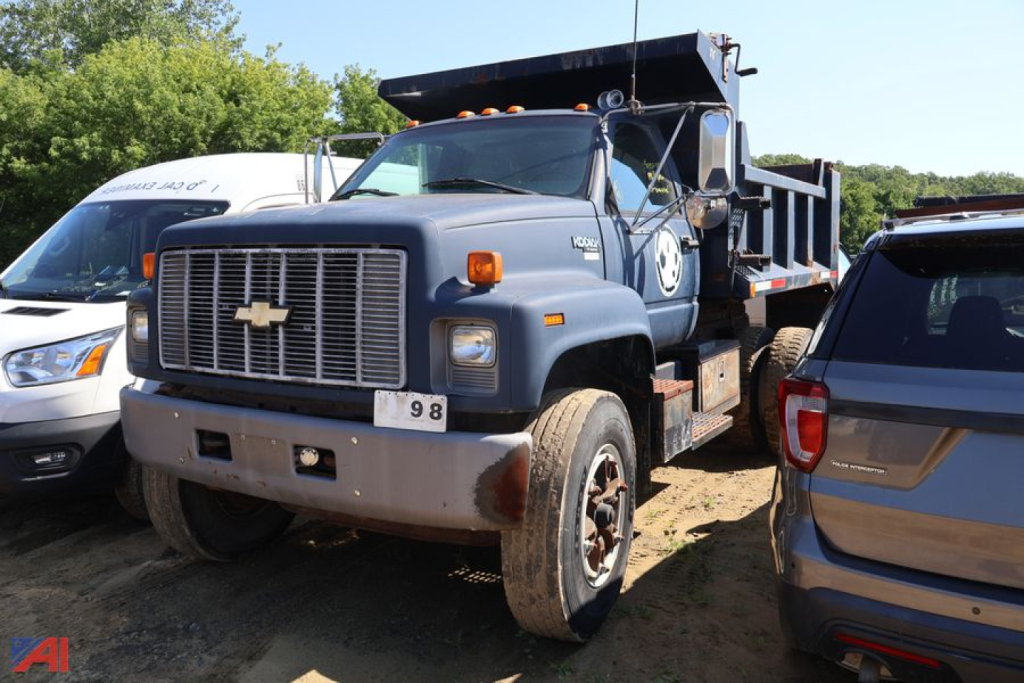 Front left view of a blue 1996 Chevrolet Kodiak C7500 dump truck with large grille, amber signal lights, and a suspended dump bed.