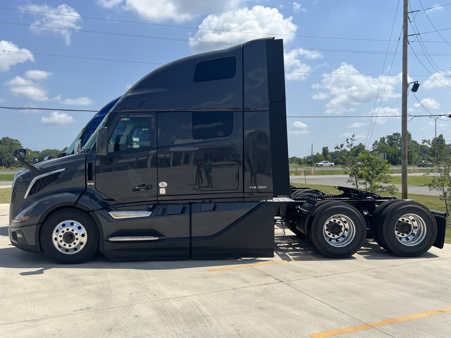 Volvo VNL64T660 sleeper cab tractor trailer in side profile with dual rear axles and dark paint; cab roof air intake and windows visible.