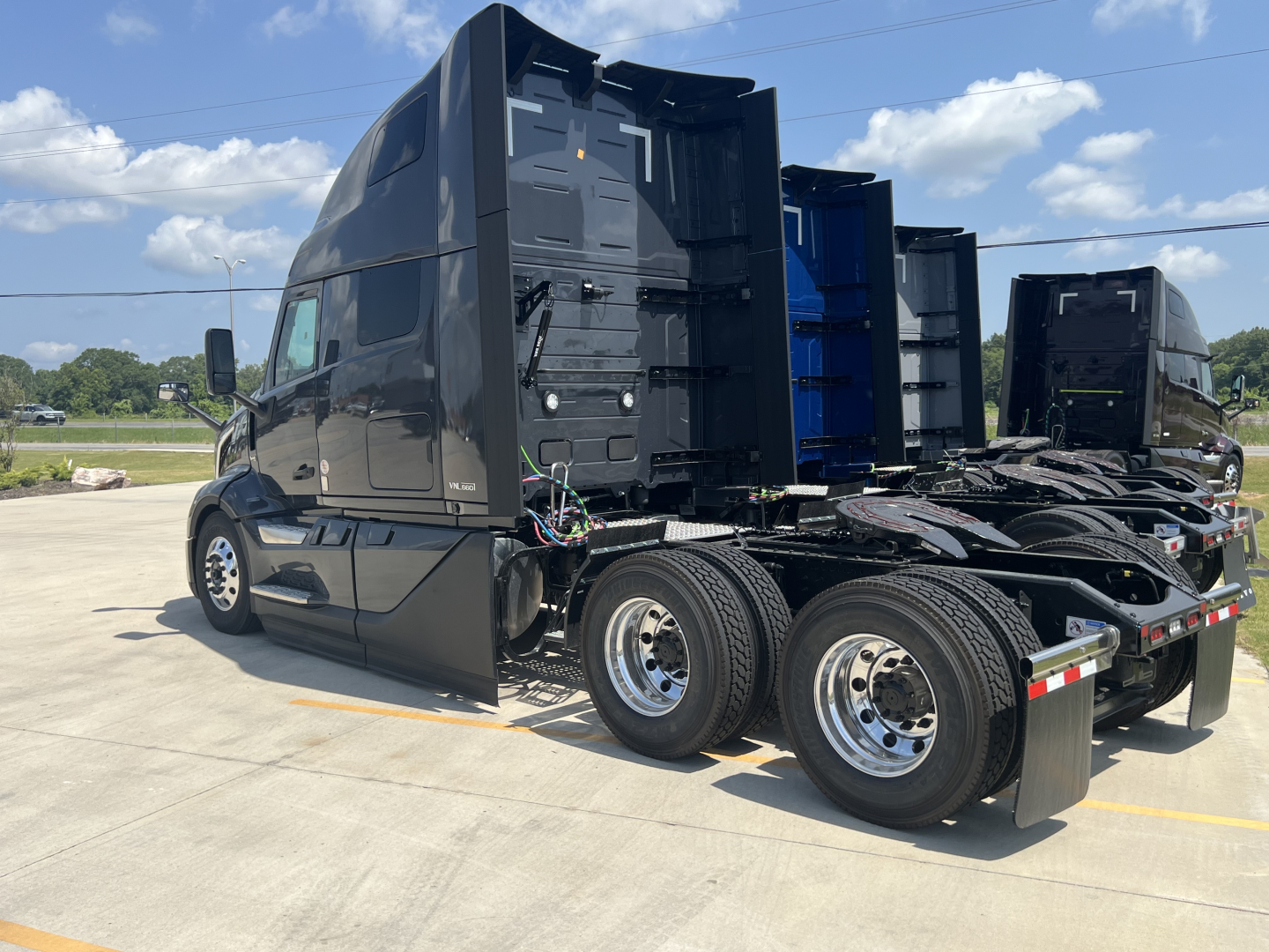 Truck tractor side view showing sleeper cab and dual rear axles with chrome wheels and black paint.