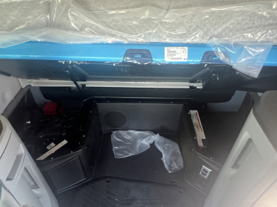Volvo VNL64T660 cabin interior view from entry, dashboard area visible with plastic cover and exposed wiring, storage basin under dash.
