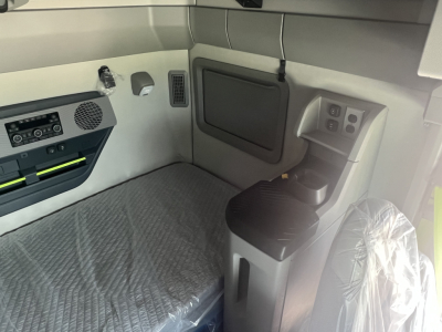 Volvo VNL64T660 sleeper cab interior showing dashboard controls, storage panel, and seat with plastic cover.