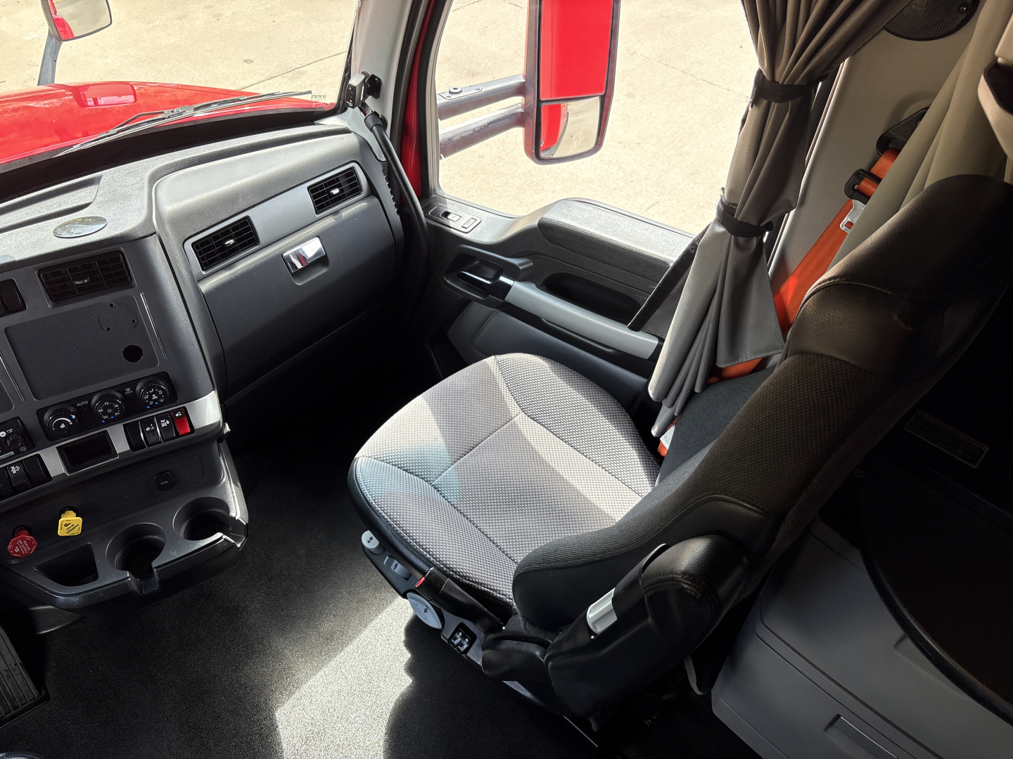 Cab interior of a 2022 Kenworth T680 truck showing driver's seat and dash with steering wheel and control panel.