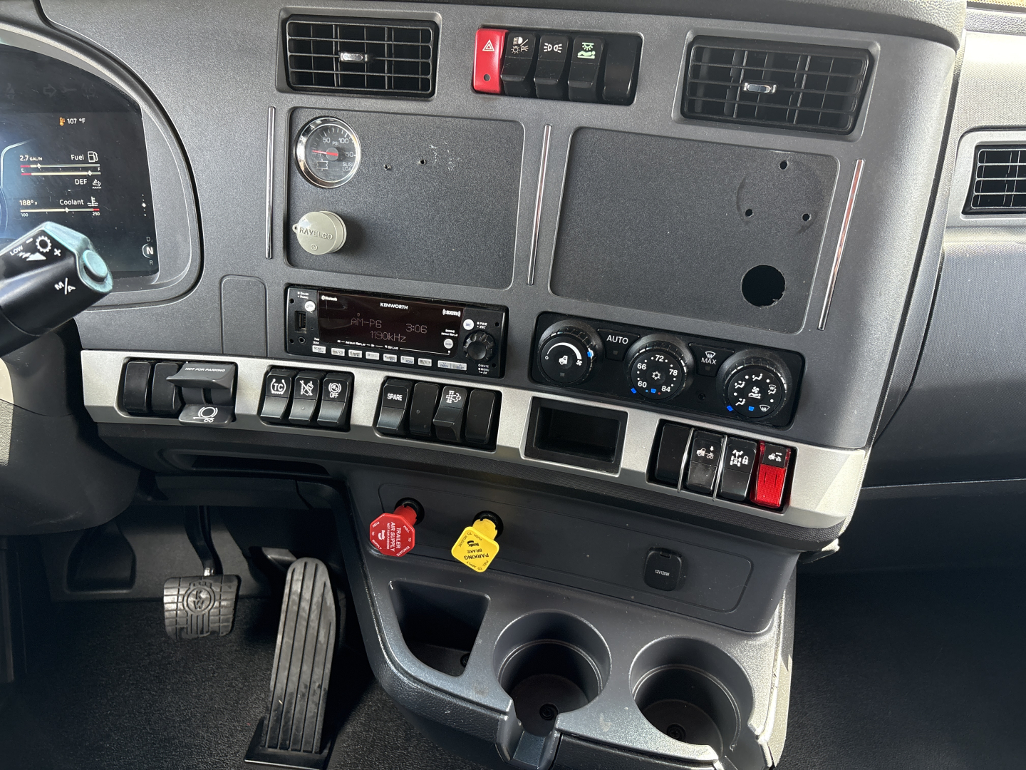 Kenworth T680 dashboard and center console showing gauges, switches, and cup holders.