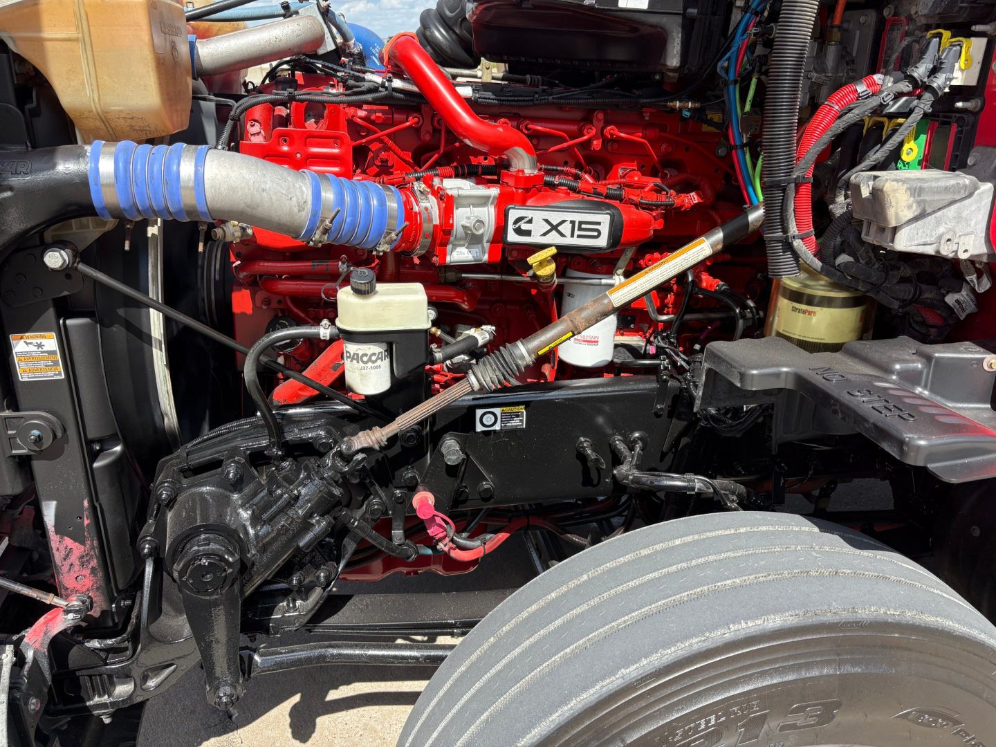Kenworth T680 engine bay showing Cummins X15 label and surrounding hoses and components.