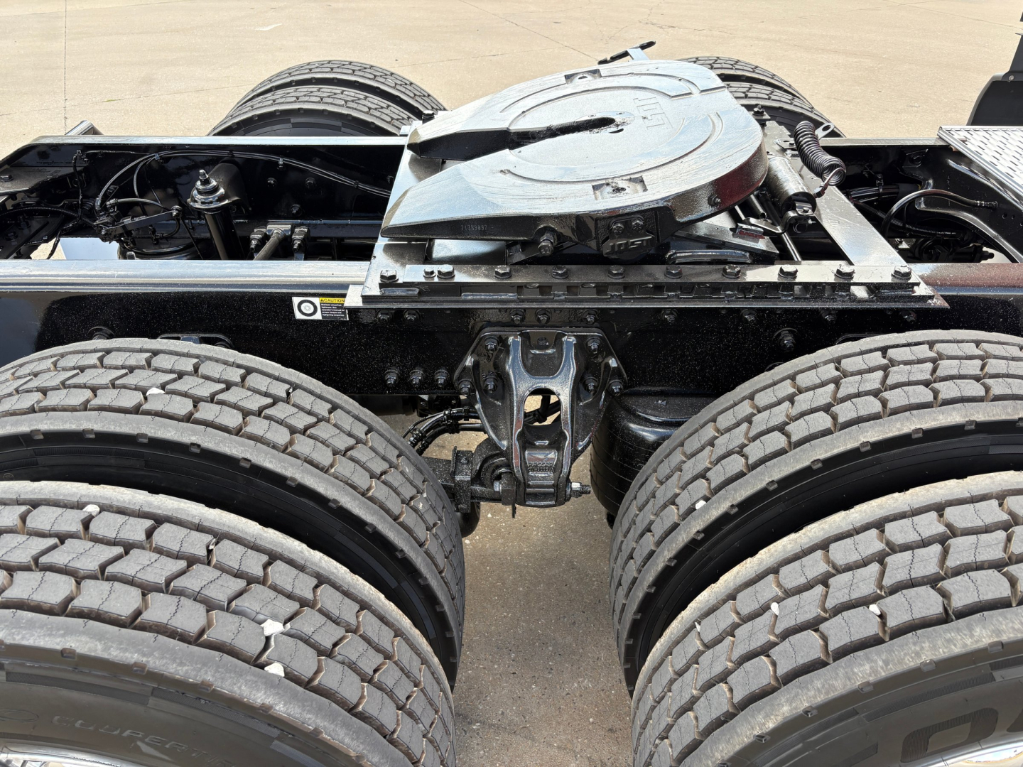 Kenworth T680 tractor rear chassis and fifth wheel area showing dual rear axles and suspension components.