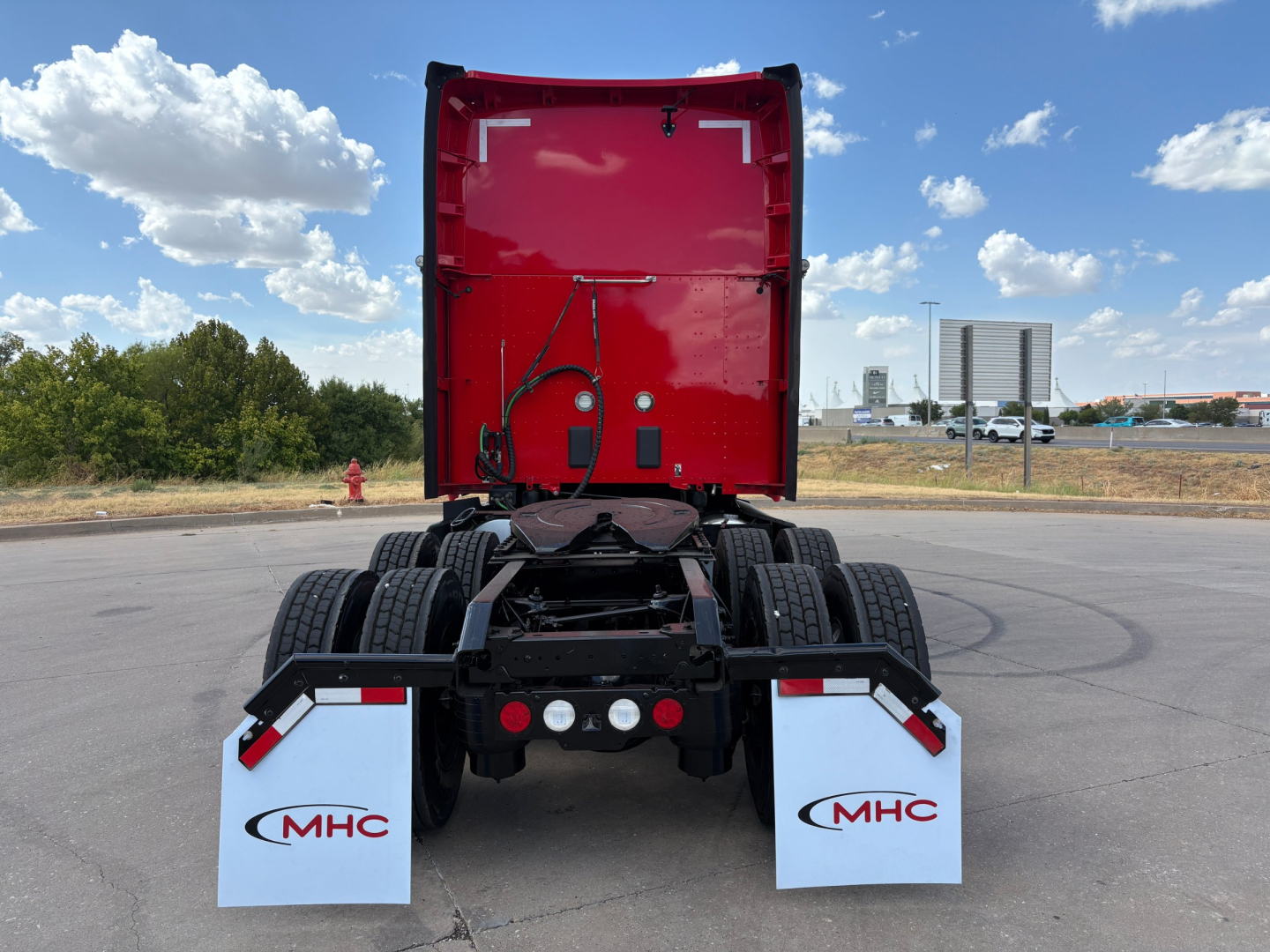 Kenworth T680 rear view showing chassis and cab-back, red sleeper cab lifted, dual rear axles with MHC mud flaps.