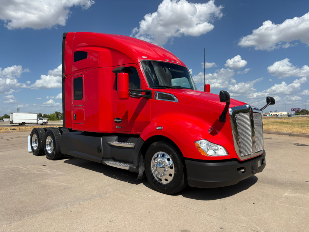 Kenworth T680 semi truck in red with sleeper cab, three rear axles, chrome wheels, front grill and side mirrors visible
