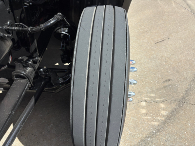 Kenworth T680 chassis with rear air suspension and a close-up of a dual-tandem drive tire along the frame; visible components include leaf springs, air lines, and wheel studs.
