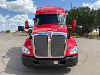Kenworth T680 truck front view showing bold chrome grille, red cab and black bumper with large mirrors.