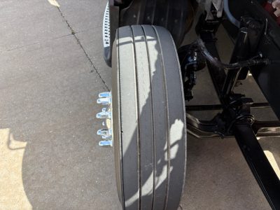 Kenworth T680 front wheel and suspension visible with tire and chrome lugs.