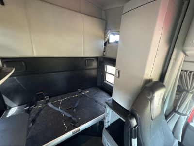 Kenworth T680 sleeper cab interior showing rear bunk area with seat and overhead storage.