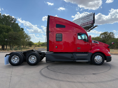 Kenworth T680 tractor-trailer side view showing red cab and black chassis, sleeper cab, two rear axles, chrome wheels, and landscape background.