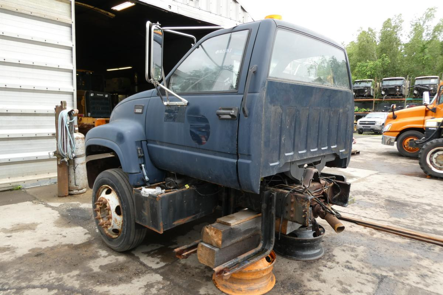 2001 Chevrolet C6500 cab and chassis viewed from rear-left showing missing front wheel and exposed underbody components.