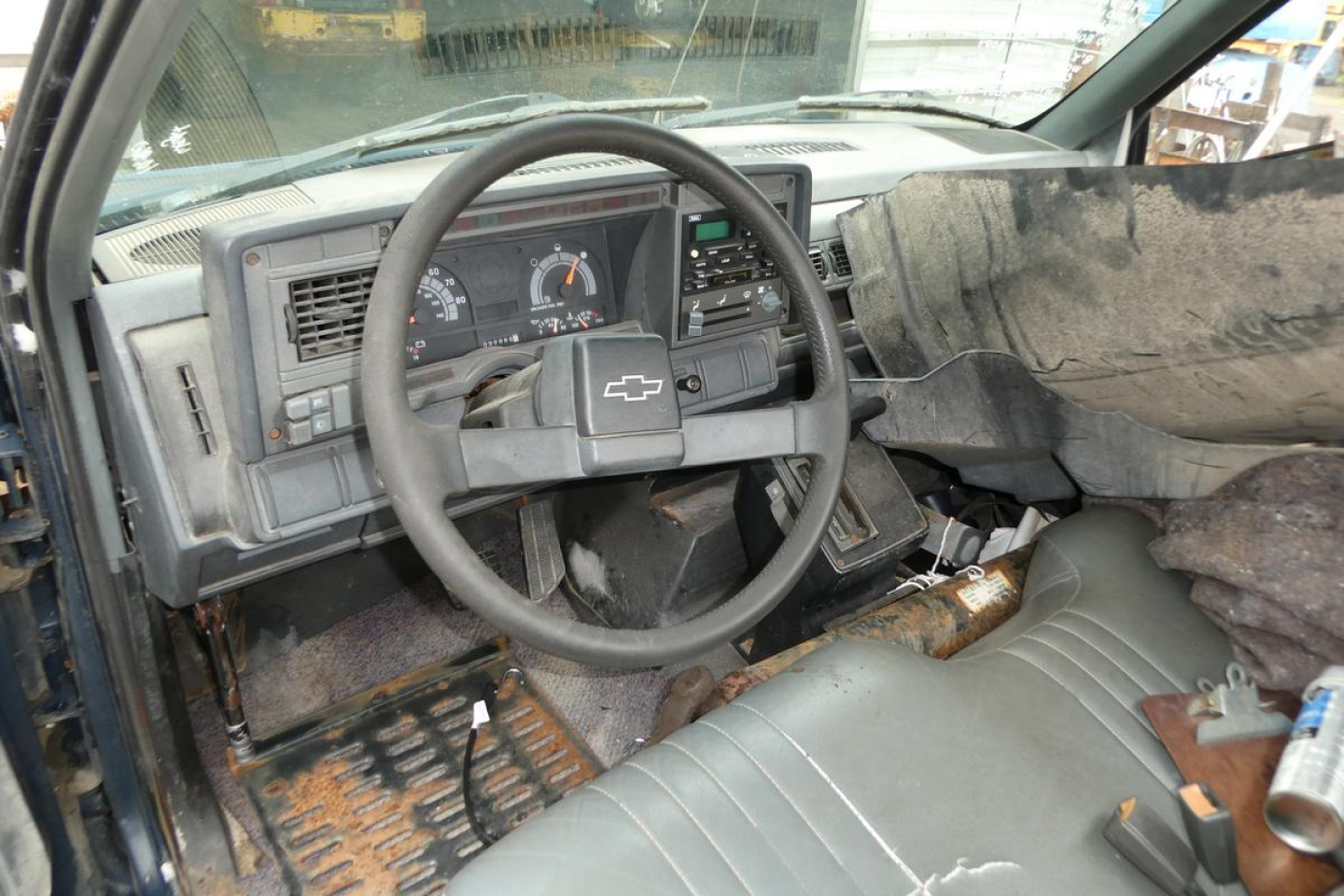 Chevrolet C6500 cab and chassis interior view showing steering wheel and dashboard with distressed vinyl seating and loose insulation.