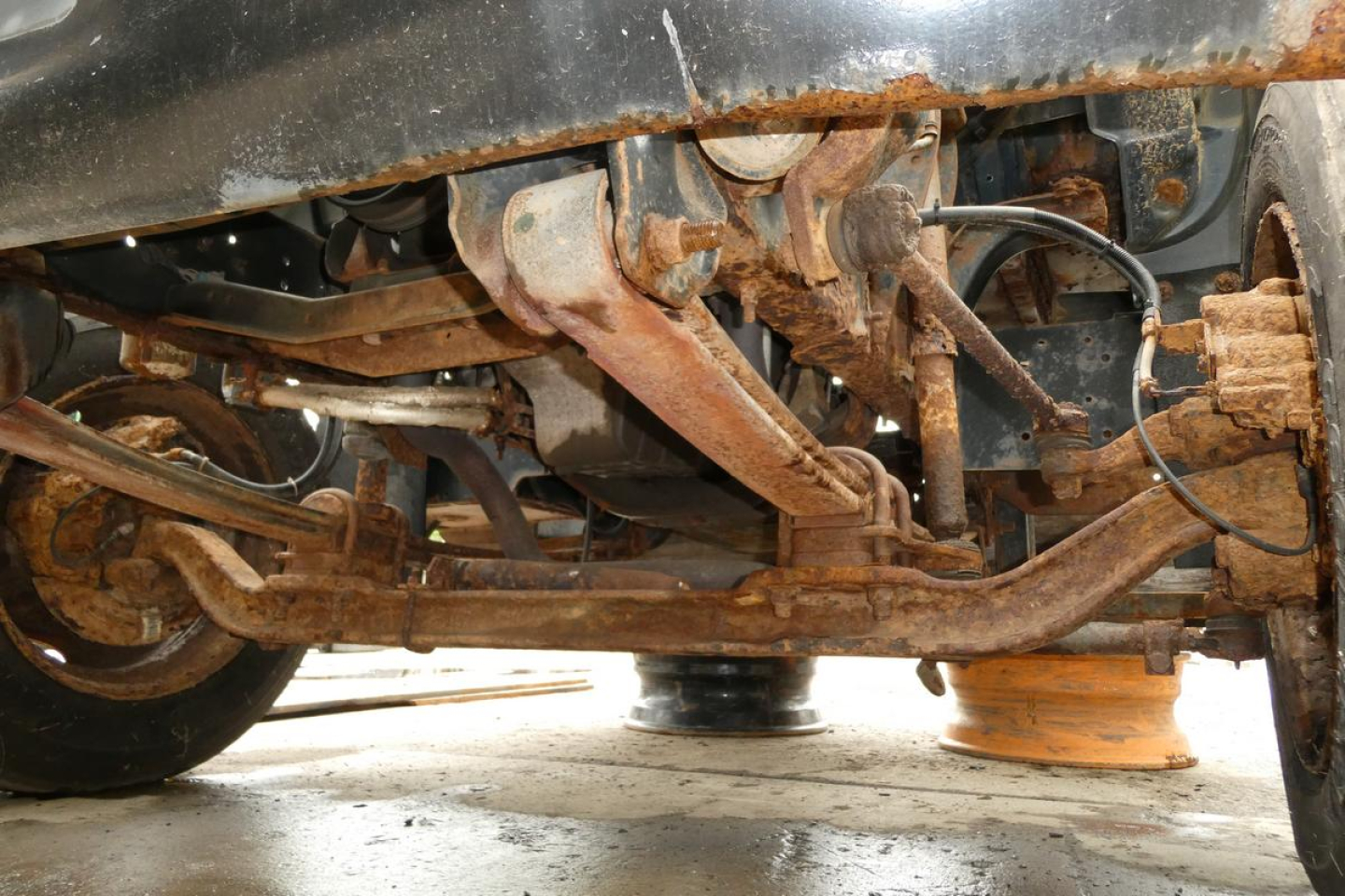 Underbody of a Chevrolet C6500 cab chassis showing rusty suspension components, leaf springs, and steering linkage.
