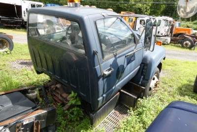 Cab and chassis truck cab showing door, windshield, and rear window with blue paint in an outdoor lot.