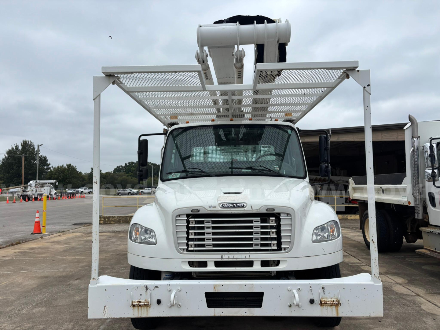 Freightliner M2 106 medium-duty bucket truck front view showing large chrome grille and white steel platform above cab for bucket lift.