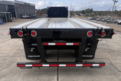 Flatbed trailer back view showing Fontaine branding on mud flaps, red taillights, and rear bumper with reflective strip. 37' combo with fracture lift kit visible.