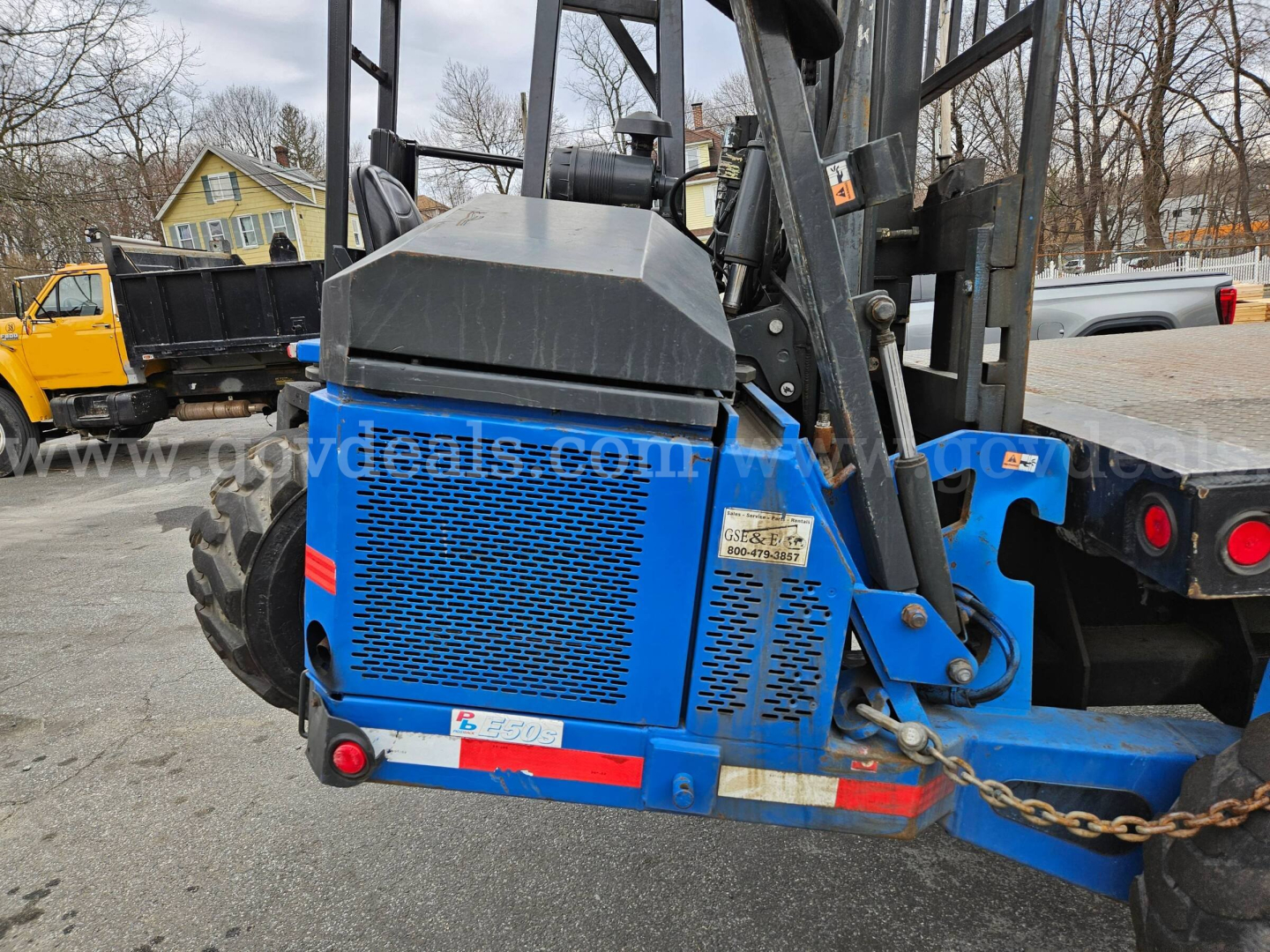 Blue Mack CV713 Granite equipment trailer/loader showing rear side with label and safety chain.
