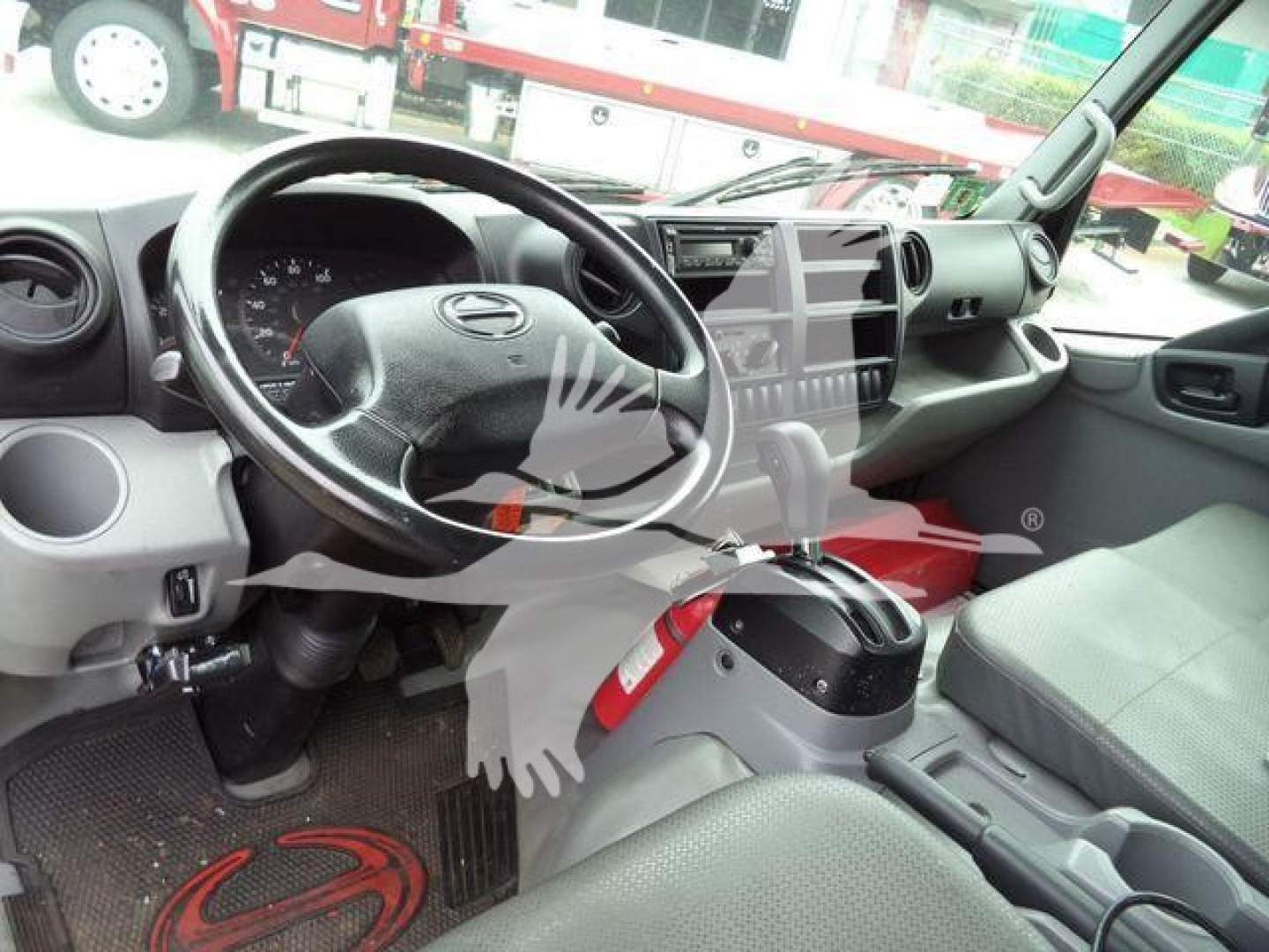 Interior of a 2019 Hino roll-off truck cab showing steering wheel, dashboard, center console, and driver's seat.