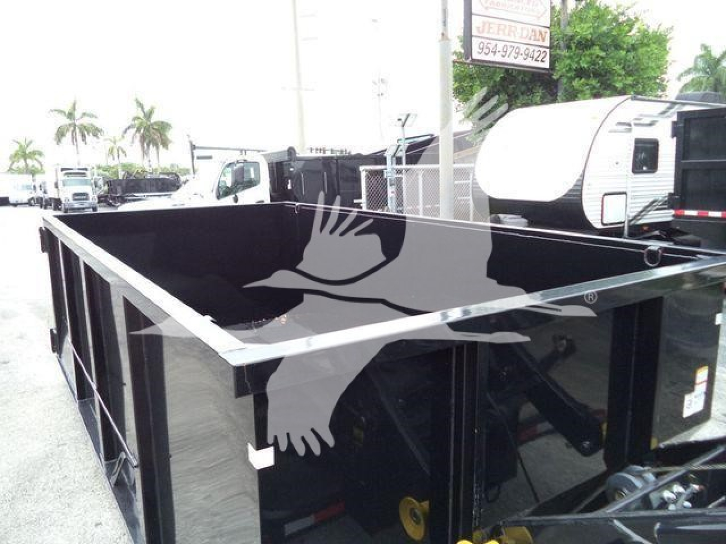 Open-top bed of a 2019 Hino 195 roll-off truck showing cargo bed sides and hydraulic components.