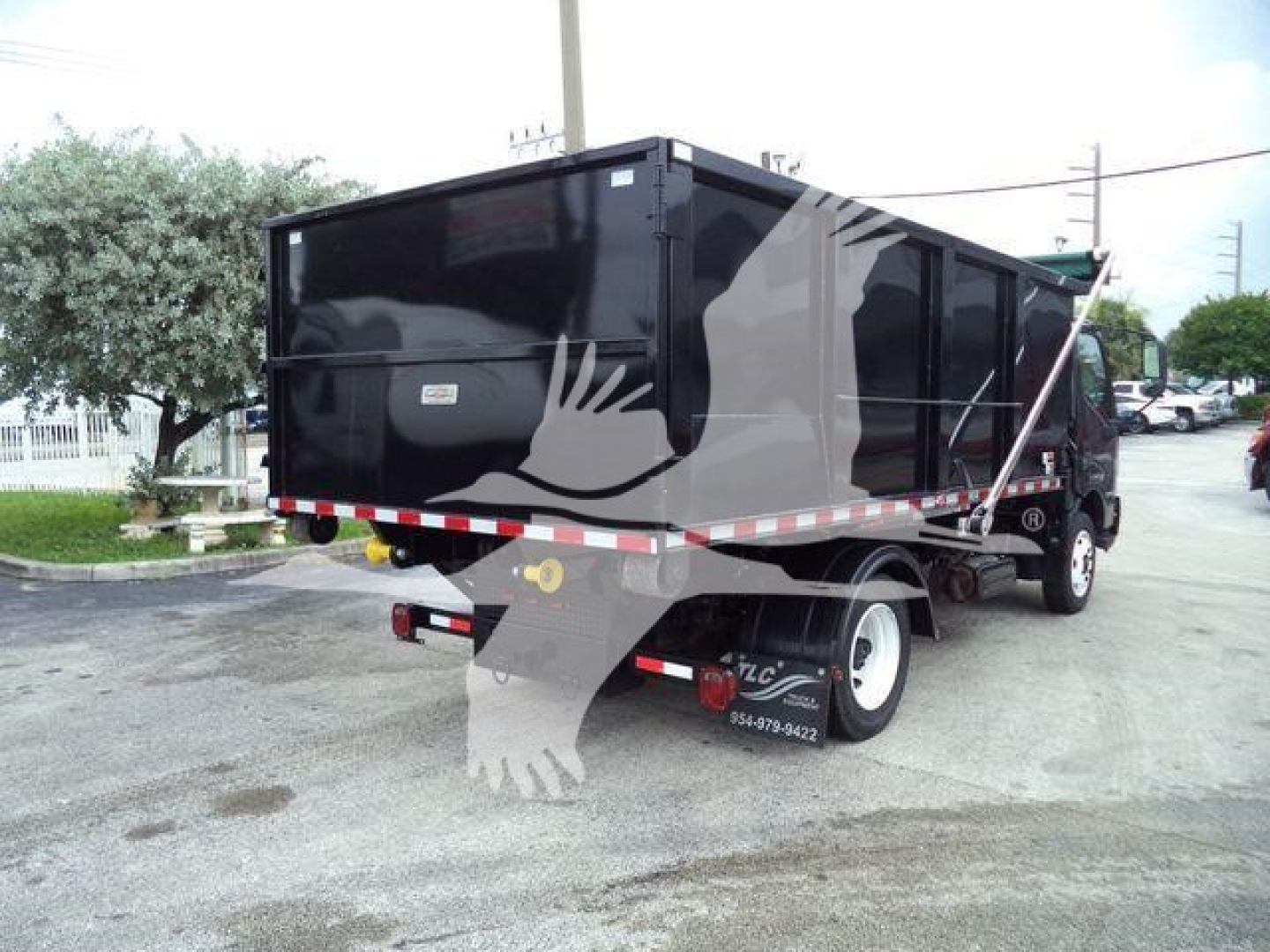 Rear and side view of a black 2019 Hino 195 roll-off truck in a used condition.