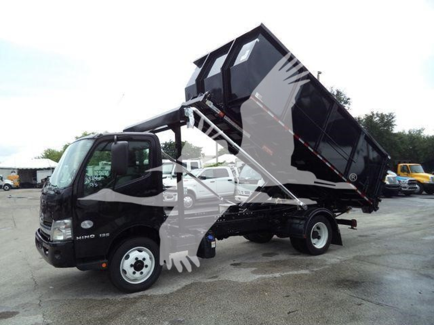 2019 Hino 195 roll-off truck with dumping body raised and hydraulic arms visible.