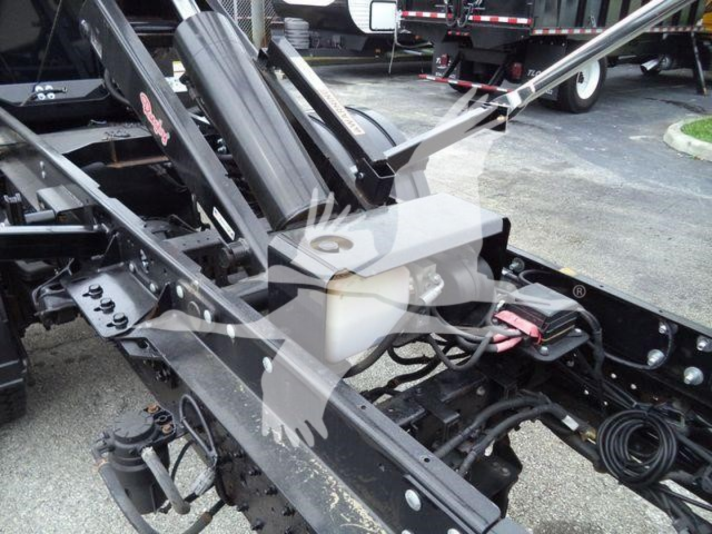 Front view of a 2019 Hino 195 roll-off truck showing hydraulic ram, frame rails, and engine bay components with wiring visible.