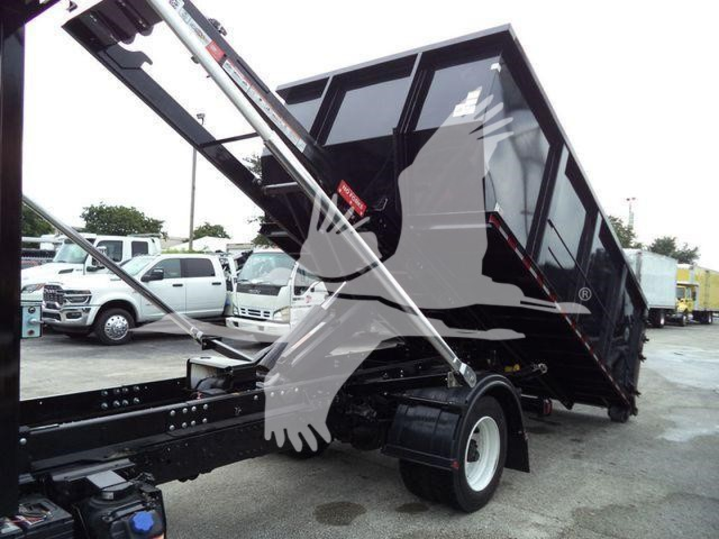 2019 Hino 195 roll-off truck in-service showing tilt bed and hydraulic arm with dump bed.