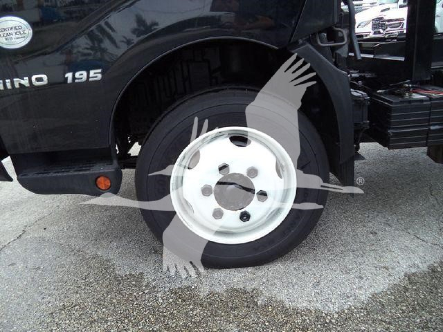 Front left wheel of a 2019 Hino 195 roll-off truck showing wheel and fender area with 'HINO 195' badge visible.
