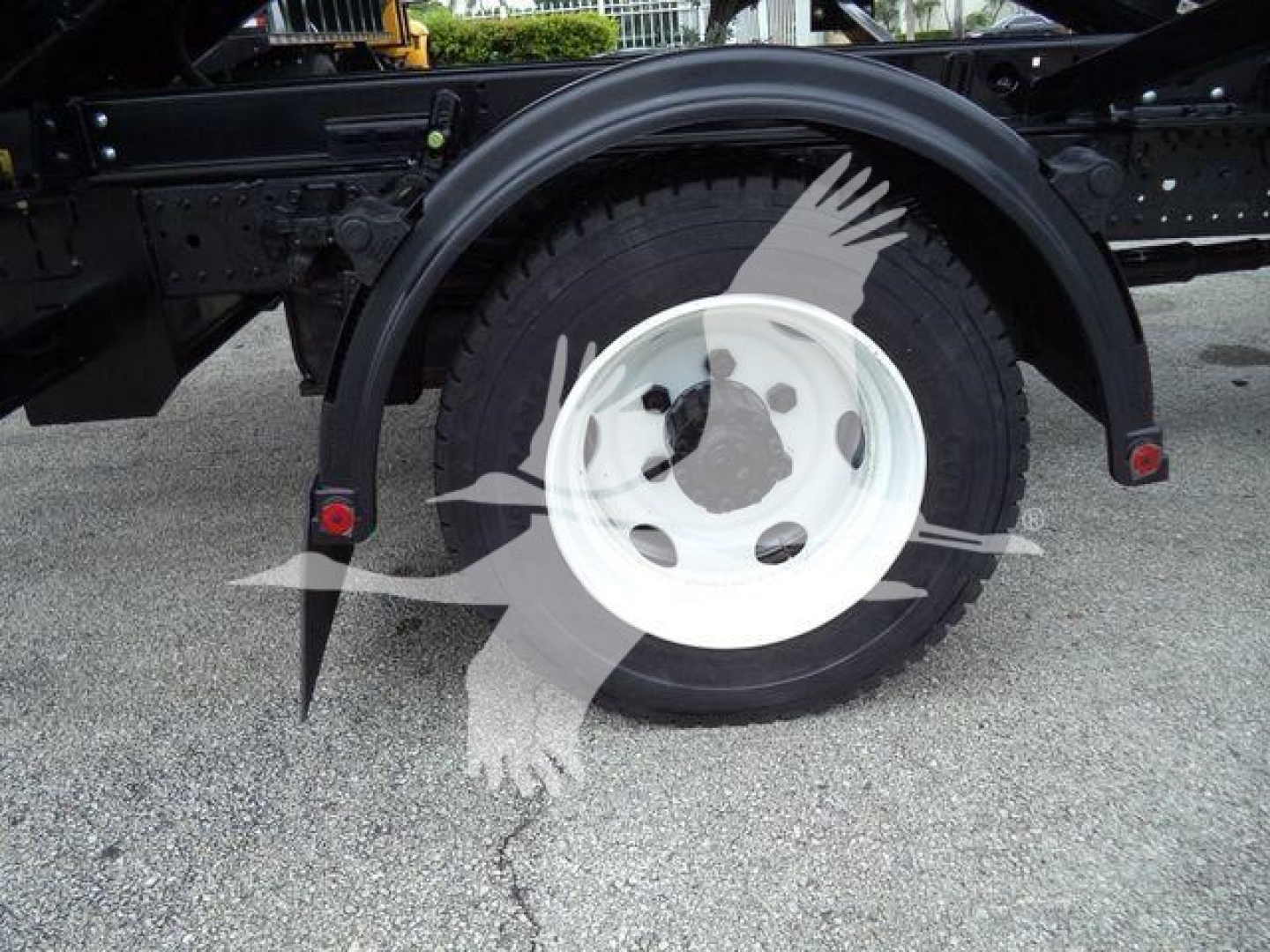 Rear wheel and fender view of a 2019 Hino 195 roll-off truck showing single rear wheel and mudflap brackets.