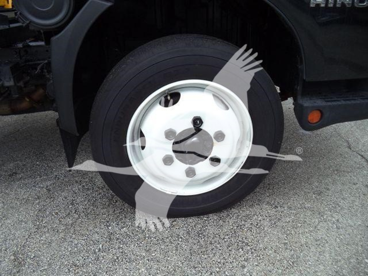 Wheel close-up of a 2019 Hino 195 rolloff truck showing front wheel and tire with white steel rim.